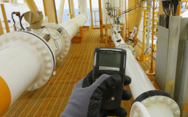 Worker holding portable gas detector.