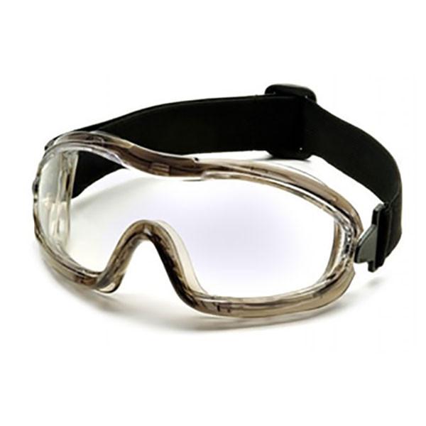 Pyramex Safety offers the Low-Profile Chemical Splash Goggle, featuring a modern sport design with clear lenses and a black adjustable strap. The transparent frame has a slight tint and curves to fit securely around the eyes for protection. These goggles meet ANSI Z87.1-2003 compliance standards.